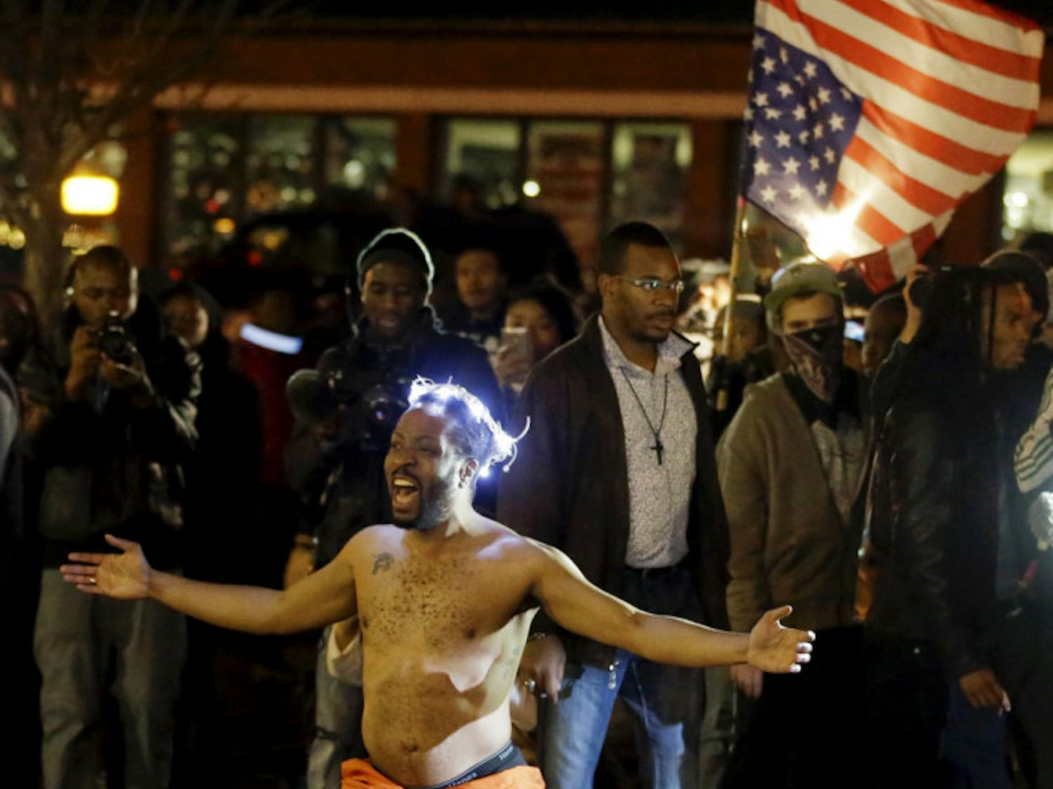 A man kneels in the middle of a street and yells at police before being arrested outside the Ferguson Police Department Saturday, Nov. 29, 2014, in Ferguson, Mo. (AP Photo/Jeff Roberson)