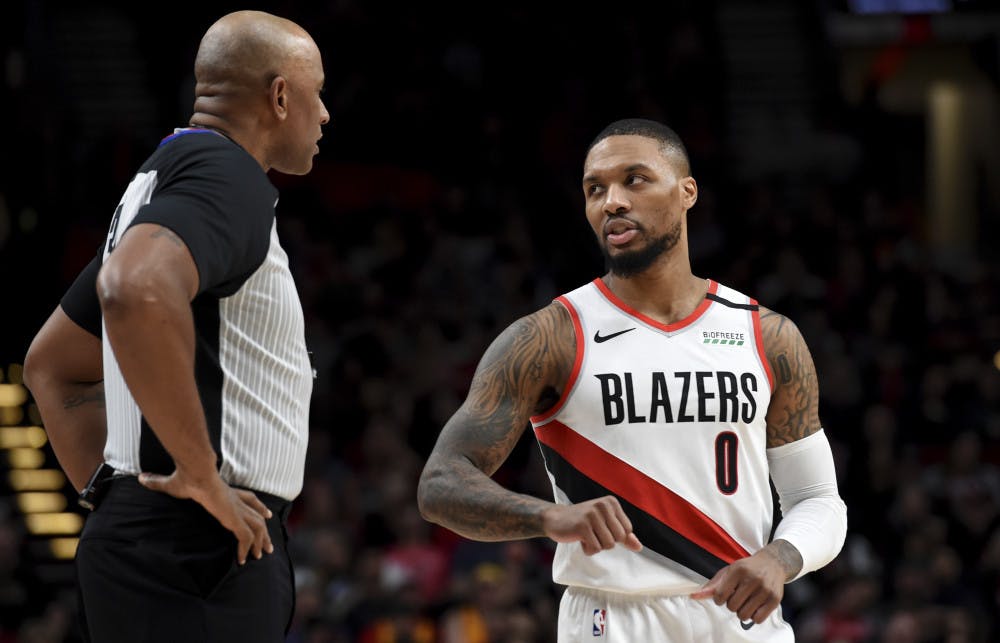 Portland Trail Blazers guard Damian Lillard, right, speaks with referee Kevin Cutler, left, during the first half of an NBA basketball game against the Utah Jazz in Portland, Ore., Saturday, Feb. 1, 2020. (AP Photo/Steve Dykes)
