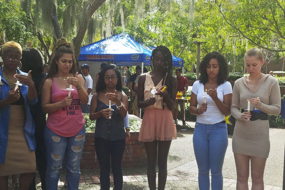 Students hold candles on Turlington Plaza at a vigil on Oct. 9, 2015, for the victims of the Oct. 1 shooting at Umpqua Community College in Oregon. Roo Poage, right, a 19-year-old UF architecture sophomore, said she was terrified when she first heard about the shooting because her close friend lives near the college.