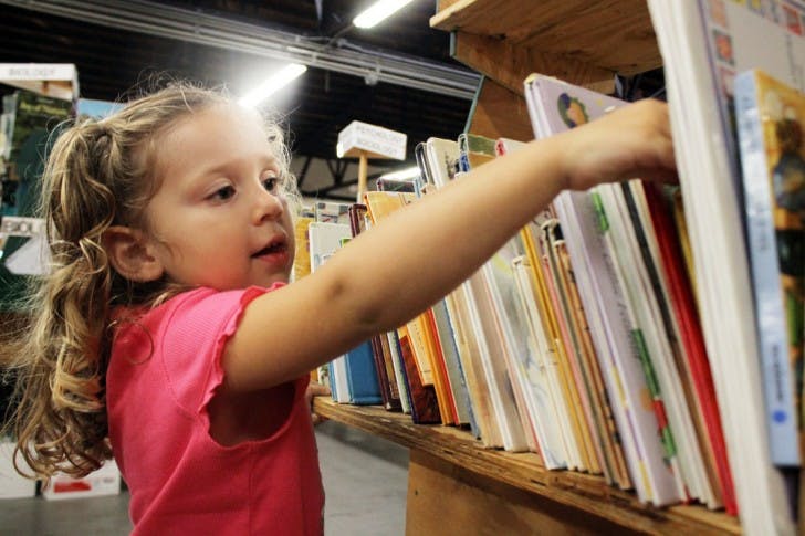 Katie Overson, 3, selects a children's book from a shelf at the Friends of the Library Book Sale on Saturday. Her mother, Marissa, said she brought Katie to the sale because Katie loves books and because she can get so many there for such low prices. The sale runs until Wednesday.