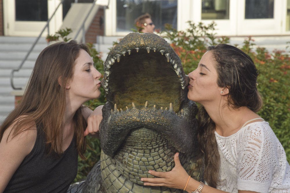 <p>Sydney Folsom, left, 23, and Sophia Saportas, 24, both UF civil engineering seniors, pose with the Bull Gator statue outside Ben Hill Griffin Stadium. Saportas said she’s very happy to finish her university years. “It’s about time,” Folsom said.</p>