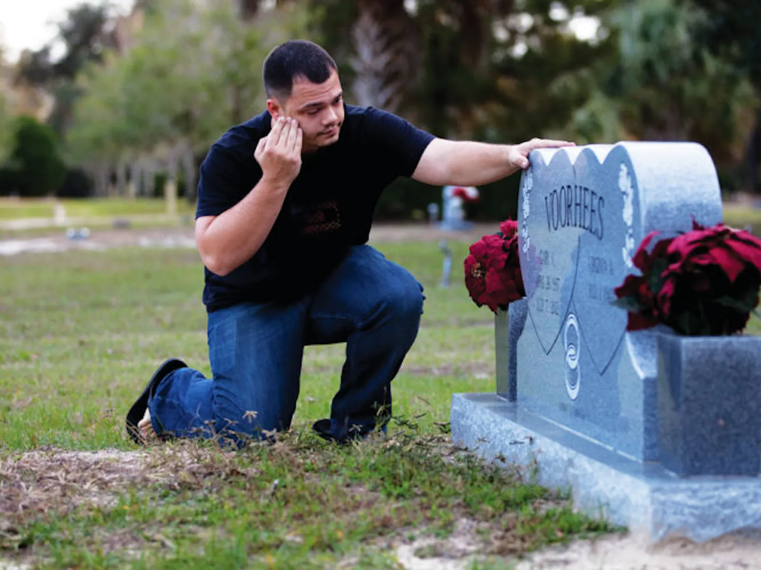 Joshua Voorhees, a 27-year-old supervisor for Neighborhood Storage in Ocala, visits his grandfather’s grave Thursday evening. Gary Voorhees died from cancer at age 75.