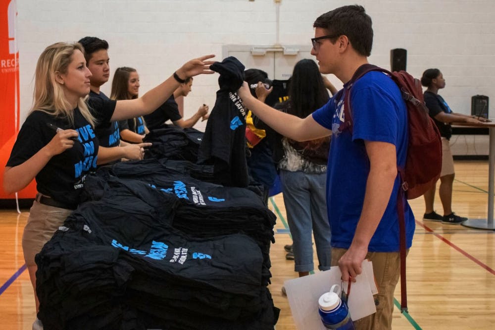 Chris Hackbardt, an 18-year-old aerospace engineering freshman, gets a free RecSports T-shirt from Haley Stark, a staff member with RecSports. Hackbardt said he was trying to go to as many events as possible and stopped by the community partners table before receiving his shirt. RecSports gave out free shirts to any student who spoke with a community partner and learned about the available resources on campus.&nbsp;