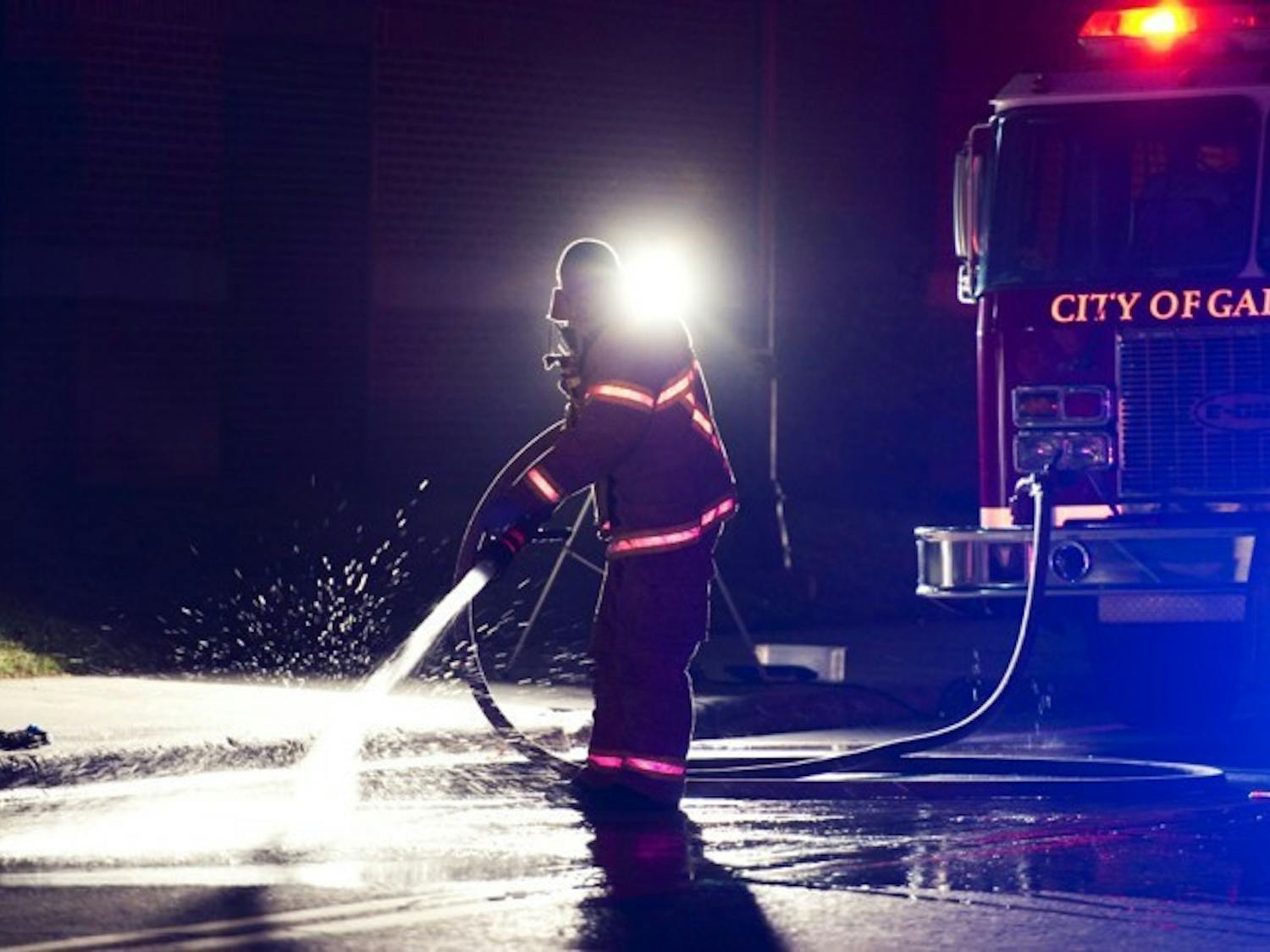 A firefighter hoses down Union Road after a chemical reactant explosion at Sisler Hall on Wednesday evening.