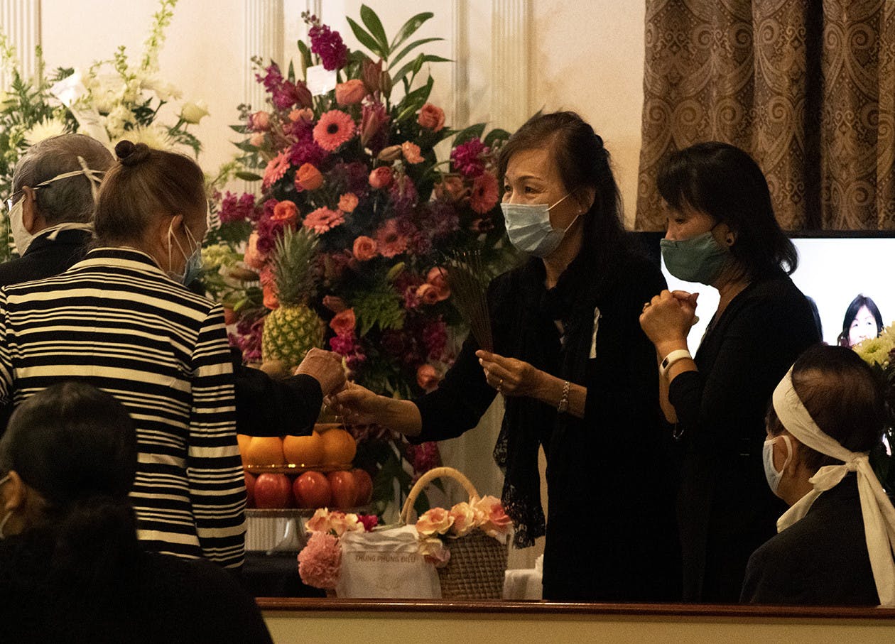 Two people hand out sticks of incense during the funeral of Bach Lien Tong Duong on Wednesday, April 14, 2021. Duong was a volunteer who taught Vietnamese at UF before an official position was created and played a significant role in creating the annual Pho fundraiser for the Vietnamese Student Organization before she passed away.