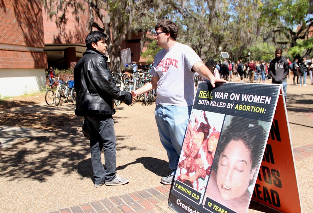 <p>Alfredo Patiño, 22, a UF senior political science and sociology major, and Joe Trammel, 22, a law student from Ohio State University and member of the Created Equal organization, shake hands. Patiño and Trammel had a respectful conversation about the images the Created Equal organization placed on Turlington Plaza on Tuesday.</p>