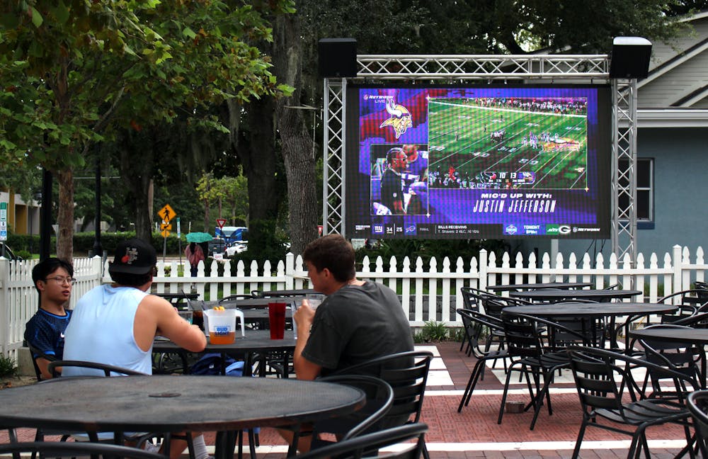 Michael Wu (left), Dante Reccoppa (center), and Caleb Farina (right) sit together outside in form of the big screen at The Swamp Restaurant on Saturday, August 9, 2025.