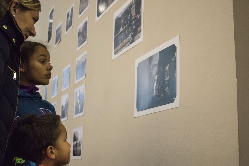 Georgia Bianchi, 41, and her children Eva Bailey, 9, and Christopher Bailey, 4, look at photos Wednesday by Venezuelan photographer Andres Avellaneda on display in the Santa Fe College Fine Arts Hall. The gallery was arranged by various Santa Fe clubs to raise funding for Avellaneda’s U.S. visa application fees.