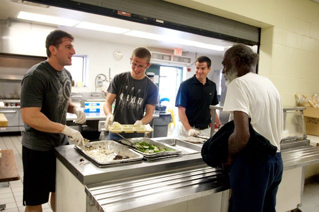 Volunteering members of RecSports serve food to a man at St. Francis House on Thursday. Currently, St. Francis House is restricted to a 130-meal limit per day.