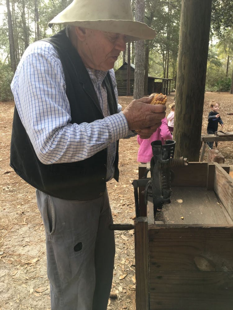 Morningside Nature Center staffer George Chappell shows visiting children how to use the corn sheller that would've been used in 1870.