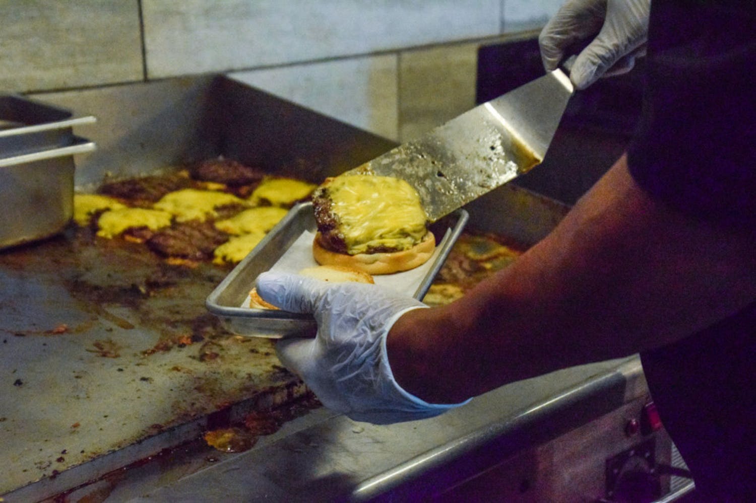 An employee prepares a cheeseburger at The Fresh Food Company.