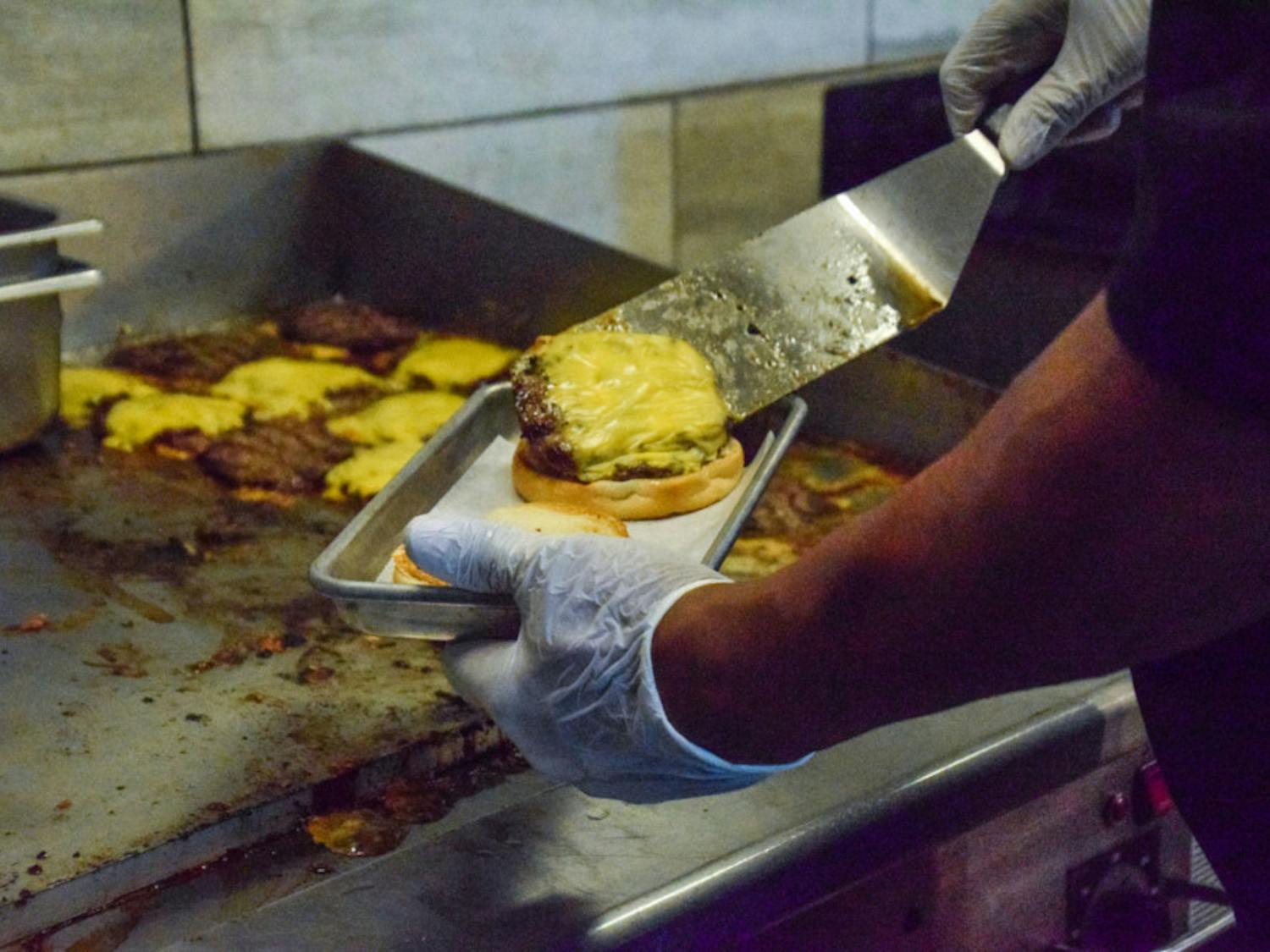 An employee prepares a cheeseburger at The Fresh Food Company.