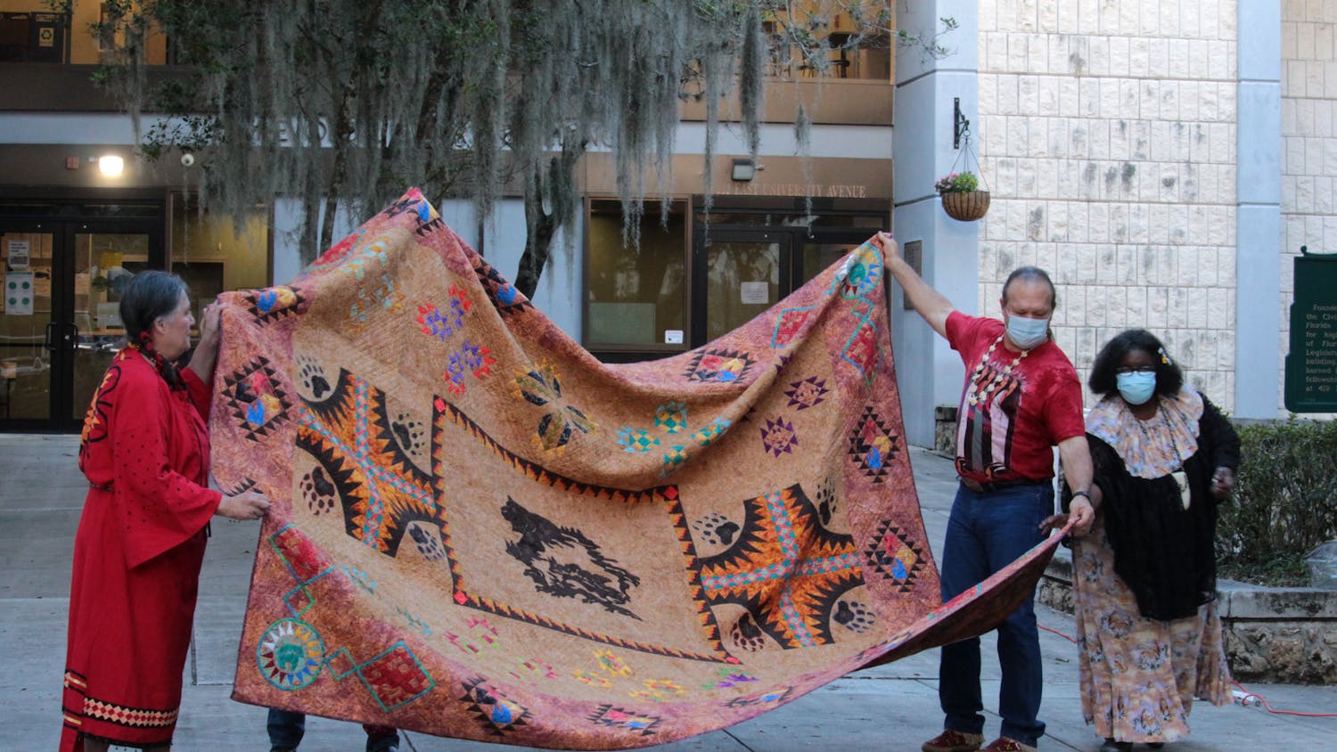 Dave Trezak (second from the right), Sioux tribe, helps to display a handmade, Native American quilt at Gainesville City Hall on Monday, Oct. 11, 2021. 