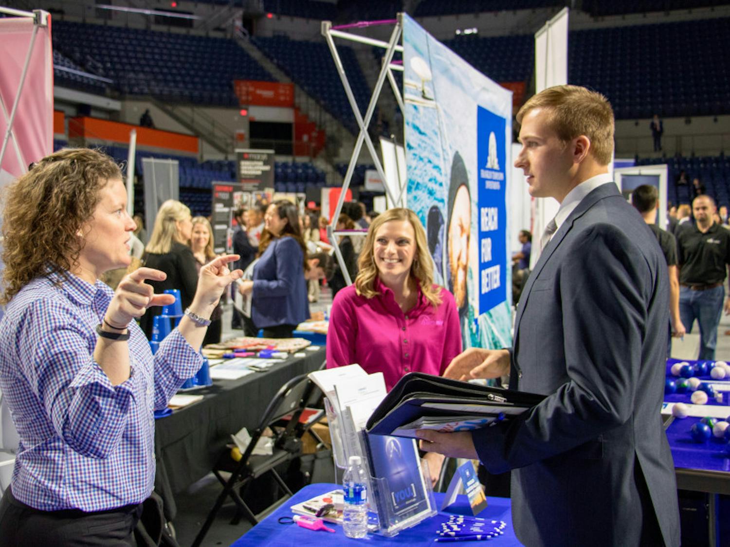 Representatives from Summit Holdings, Inc. speak to a student about the different opportunities at their company. Summit was one of the hundreds of firms and organizations present at Career Showcase in the Stephen C. O'Connell Center on Tuesday morning.