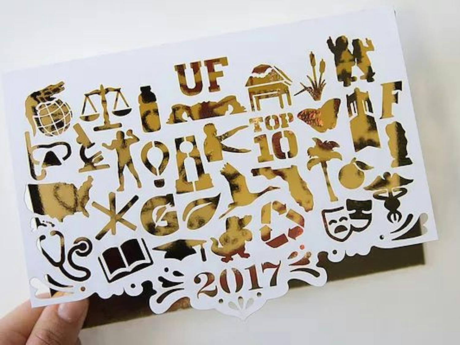 The winning card features 32 icons, which represent categories that make UF unique, cut out on white paper over gold foil. The message inside the winning card reads “Warmest Wishes,” which Jones described as a play on words about Florida’s hot weather.