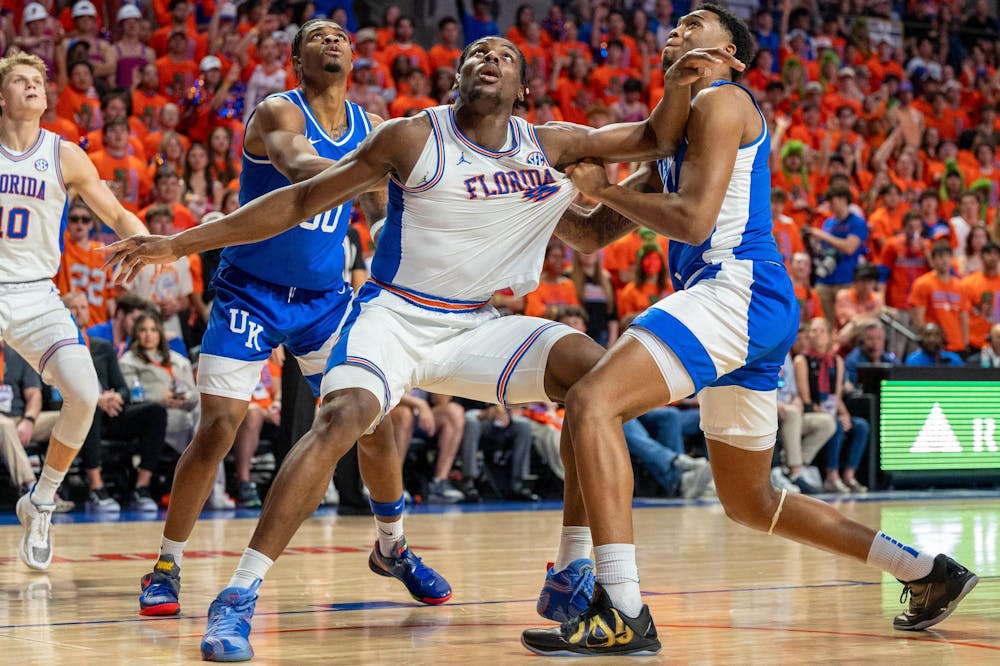Florida center Rueben Chinyelu (9) reaches for the rebound against two Kentucky guards during the first half of an NCAA college basketball game, Saturday, Feb. 14, 2026 at Exactech Arena in Gainesville, Fla.