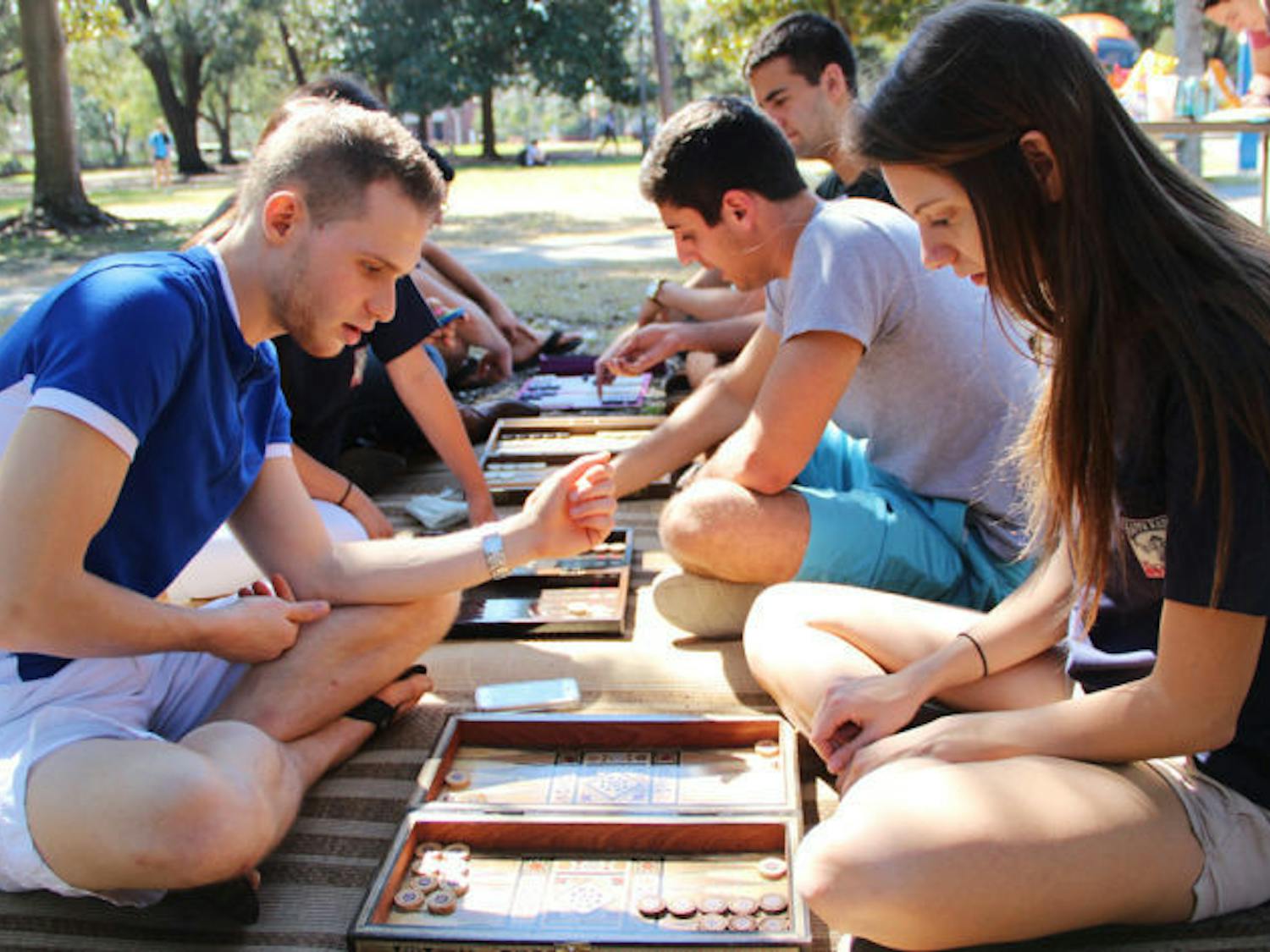 Shai Zarif, a 20-year-old UF computer science junior, guides 20-year-old UF public relations sophomore Lauren Morris through a game of Shesh-Besh on the Plaza of the Americas on Wednesday.