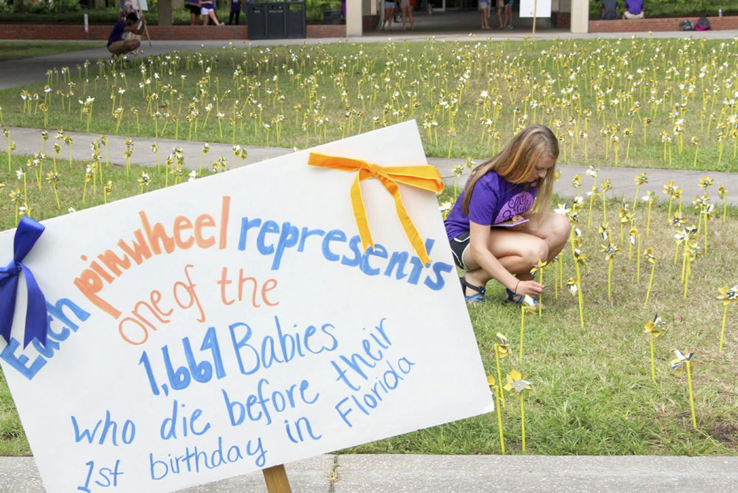 UF biology sophomore Kallie Erickson, 19, plants gold pinwheels outside Library West for the 11th annual Gators March for Babies on Wednesday afternoon. The march will take place Nov. 16.