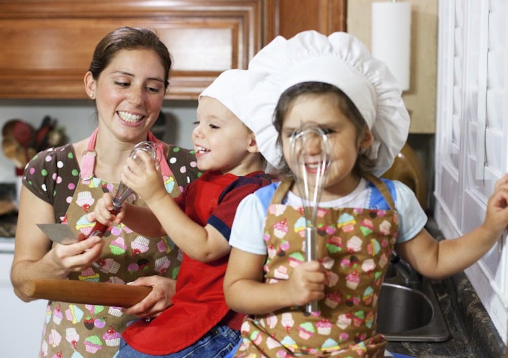 <p>Sherrie Blackwelder’s children Isabella, 4, and Ira, 2, wield their favorite baking utensils with their mother on Monday night at their home in Gainesville. Blackwelder makes cakes and other desserts out of her home for her business, Cake Classics.</p>