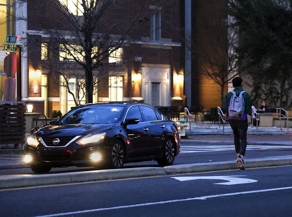 A pedestrian jaywalks across West University Avenue on Wednesday, Feb. 17, 2021.