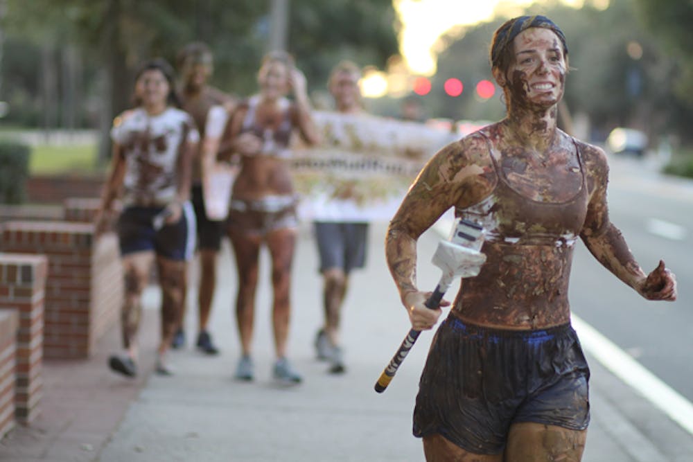 <p>Mud-splattered Chantel Carter, 23, runs along University Avenue with four friends Tuesday evening promoting Gator Mud Run, a 5K race and paramilitary-style obstacle course on Nov. 6.</p>