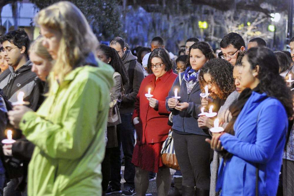 A group of people gather to participate in a vigil on Turlington Plaza on Friday night in memory of the victims from the Tuesday shootings in Chapel Hill, North Carolina.