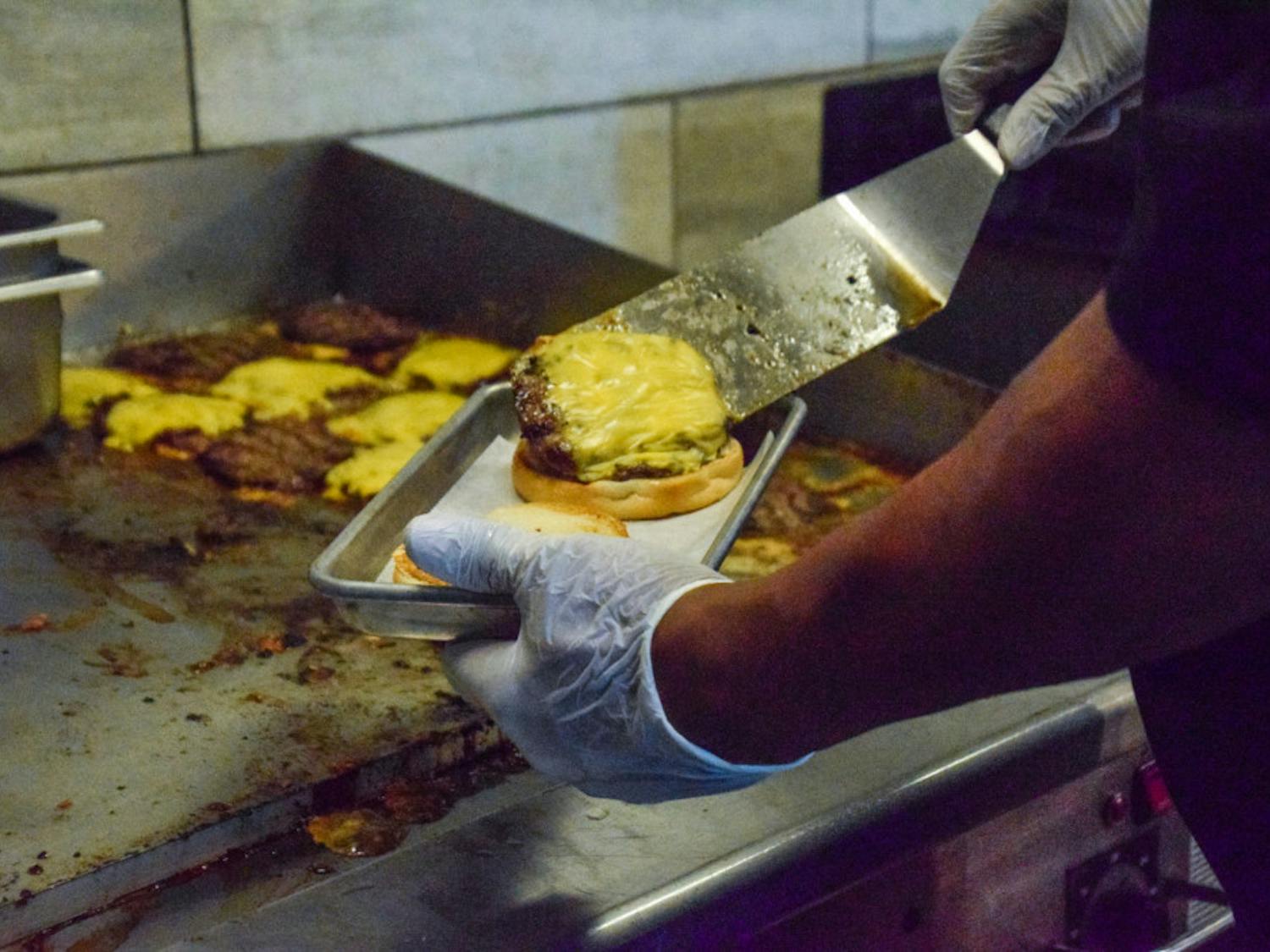 An employee prepares a cheeseburger at The Fresh Food Company. The 2019 Food Service Master Plan by Brailsford &amp; Dunlavey and Petit Consulting said that Aramark’s food in the UF dining halls isn’t fresh.
