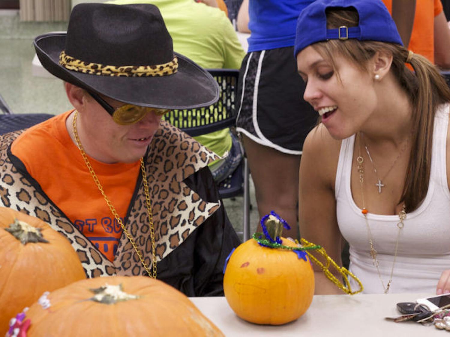 UF criminology freshman Deirdre Pearsall, 18, helps Gainesville resident Chris Brown, 34, decorate a pumpkin for the party hosted by Best Buddies at the Broward Hall Basement on Wednesday evening.