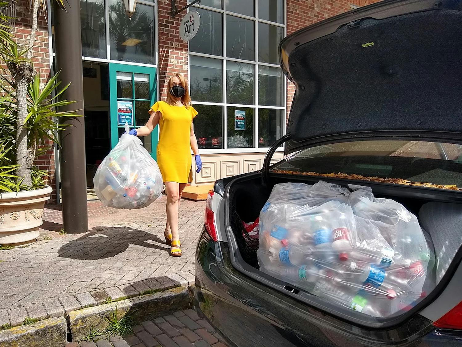 Iryna Kanishcheva holds recycled bottles in front of Black C Art Gallery. (Photo courtesy of Black C Art Gallery by Ani Collier)
