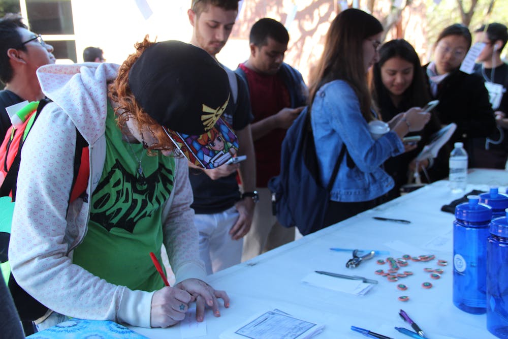 <p><span>Students line up to write quotes about diversity and immigration that were later hung above the UF Chispas table and tent. After writing a quote, students took a photo and were given a free Hyppo ice pop. </span></p>