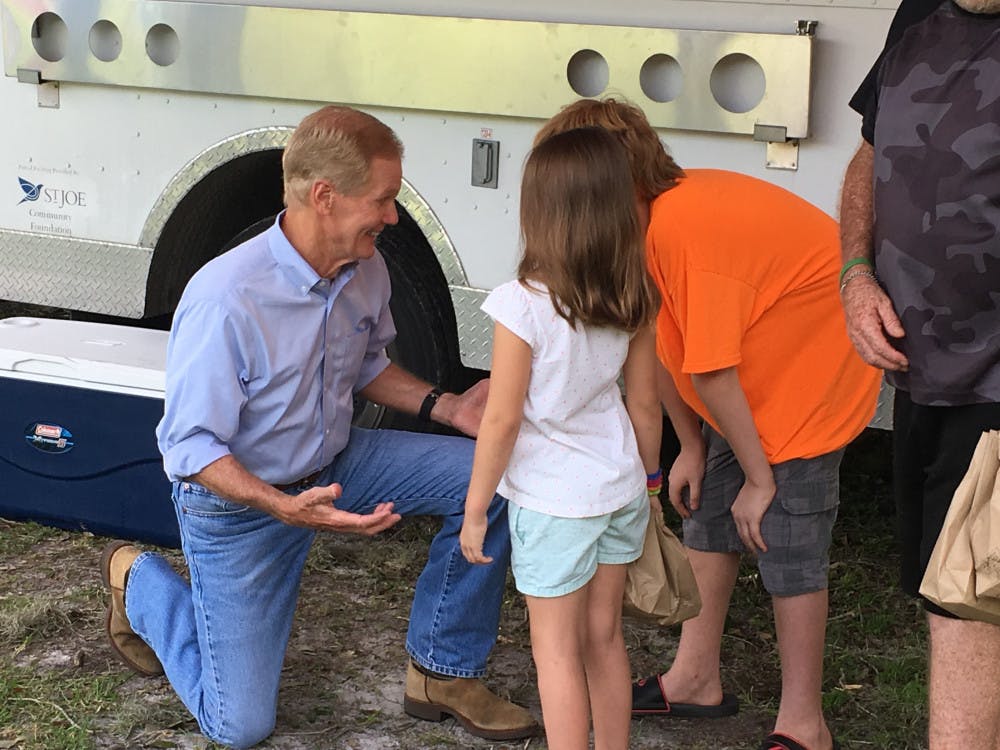 Sen. Bill Nelson chats with 9-year-old Alicia, her older brother, 12-year-old Jefrey, and their grandfather, 60-year-old Danny Harrell, at a Salvation Army lunch event on Thursday at Maddox Park, located at 129th Place, for Archer residents without power or water after Hurricane Irma.