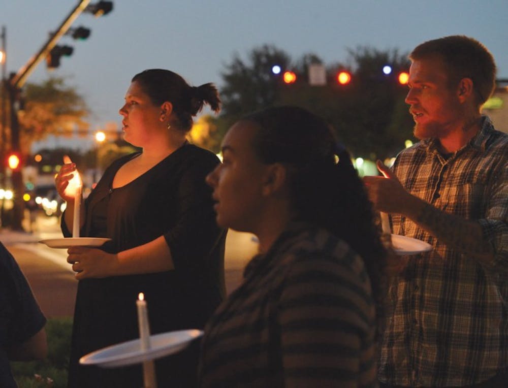 <p>Gainesville residents Jessica Canterbury, 24, left, and Shane Russell, 24, right, participate in a candlelight vigil for missing UF student Christian Aguilar on the corner of Southwest 13th Street and West University Avenue. Aguilar went missing on Sept. 20, and numerous police and volunteer led searches have turned up nothing.</p>