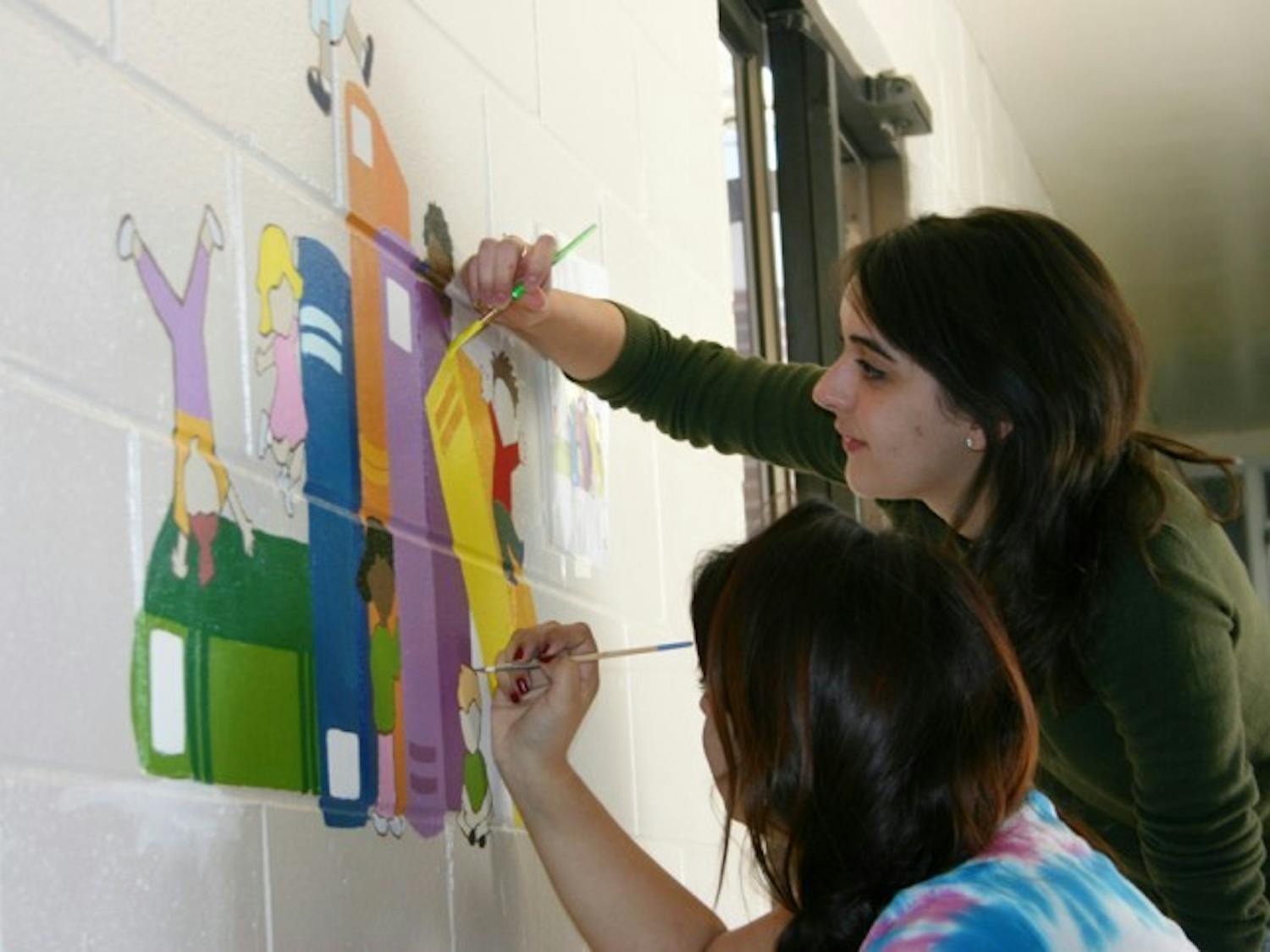 Lesly Parra, an 18-year-old advertising freshman, and Sasha Saigol, a 19-year-old marketing freshman, perfect a mural in a Chester Shell Elementary School hallway Saturday. They volunteered their time as a part of Project Makeover, an organization that fixes up one Alachua County school each year.