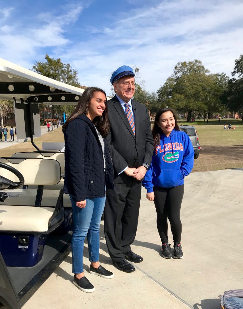 UF President Kent Fuchs poses with students in front of his Gator-themed golf cart. He drove students back and forth between campus locations on the first day of classes. 