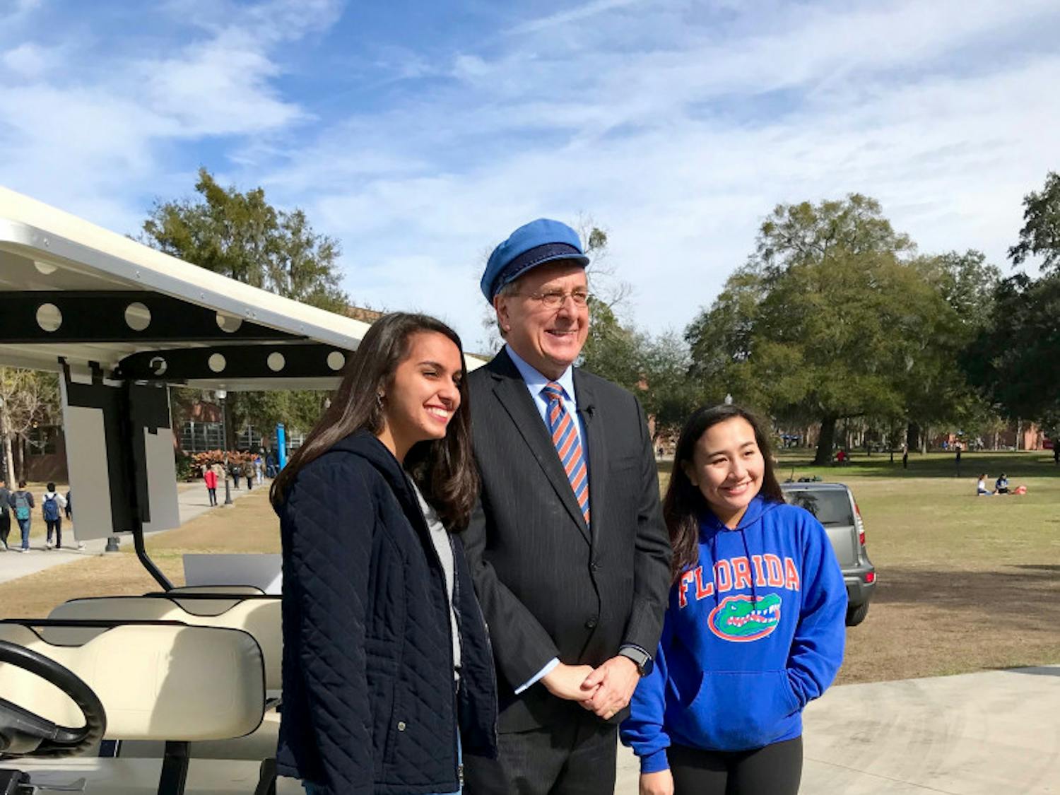 UF President Kent Fuchs poses with students in front of his Gator-themed golf cart. He drove students back and forth between campus locations on the first day of classes.