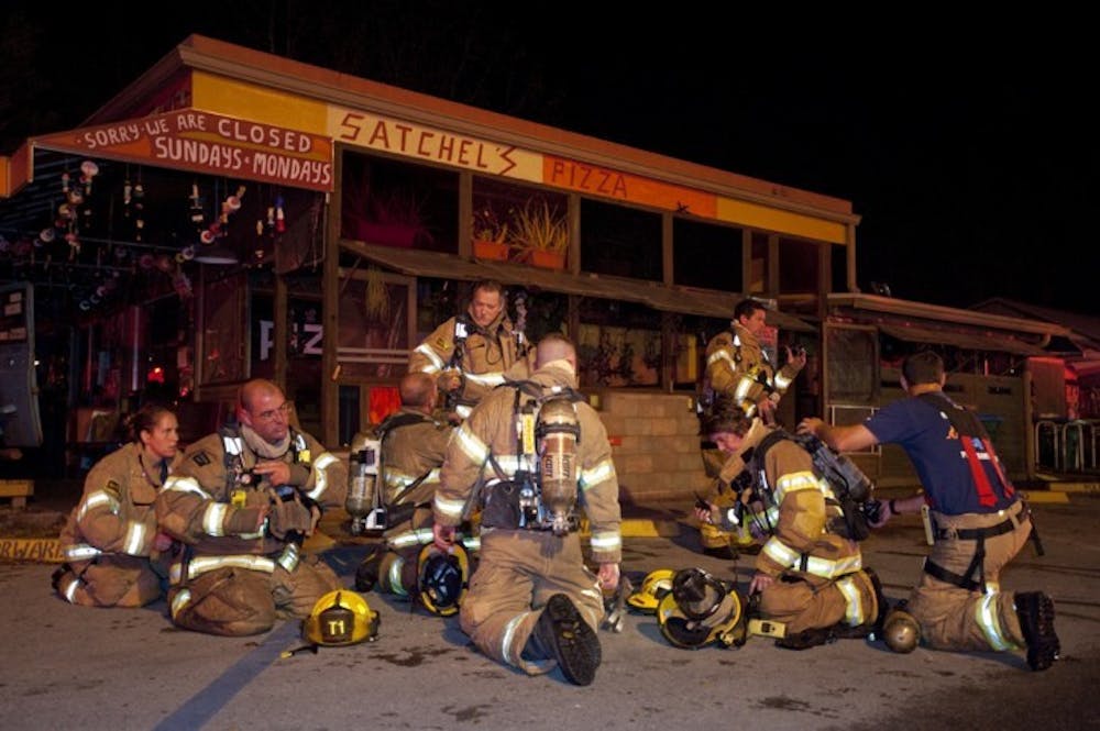 <p>Gainesville Fire Rescue workers sit outside Satchel's Pizza on Tuesday night.</p>