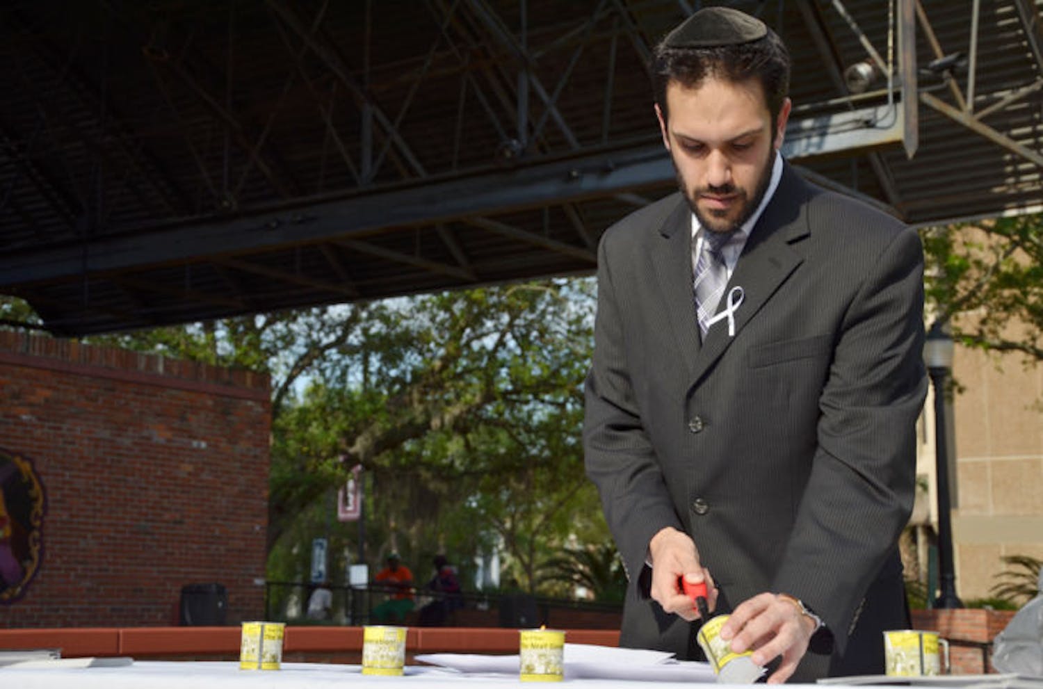 Rabbi Daniel Wolnerman, of UF Hillel, lights a candle at a memorial ceremony commemorating genocide victims on Bo Diddley Community Plaza on Sunday. April is Genocide Awareness Month.