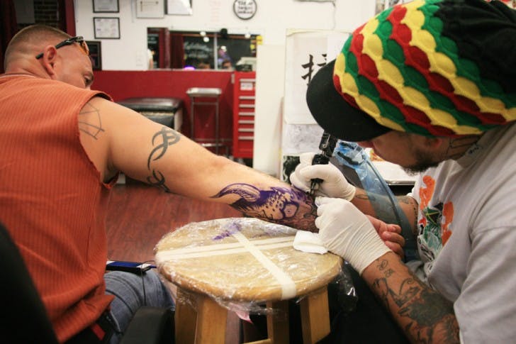 Santa Fe College health science freshman Charles Quinlan, 32, endures the pain of a custom tattoo by Mike Taylor, 23, at Addiction Tattoo and Piercing, 819 W. University Ave., on Sunday evening.