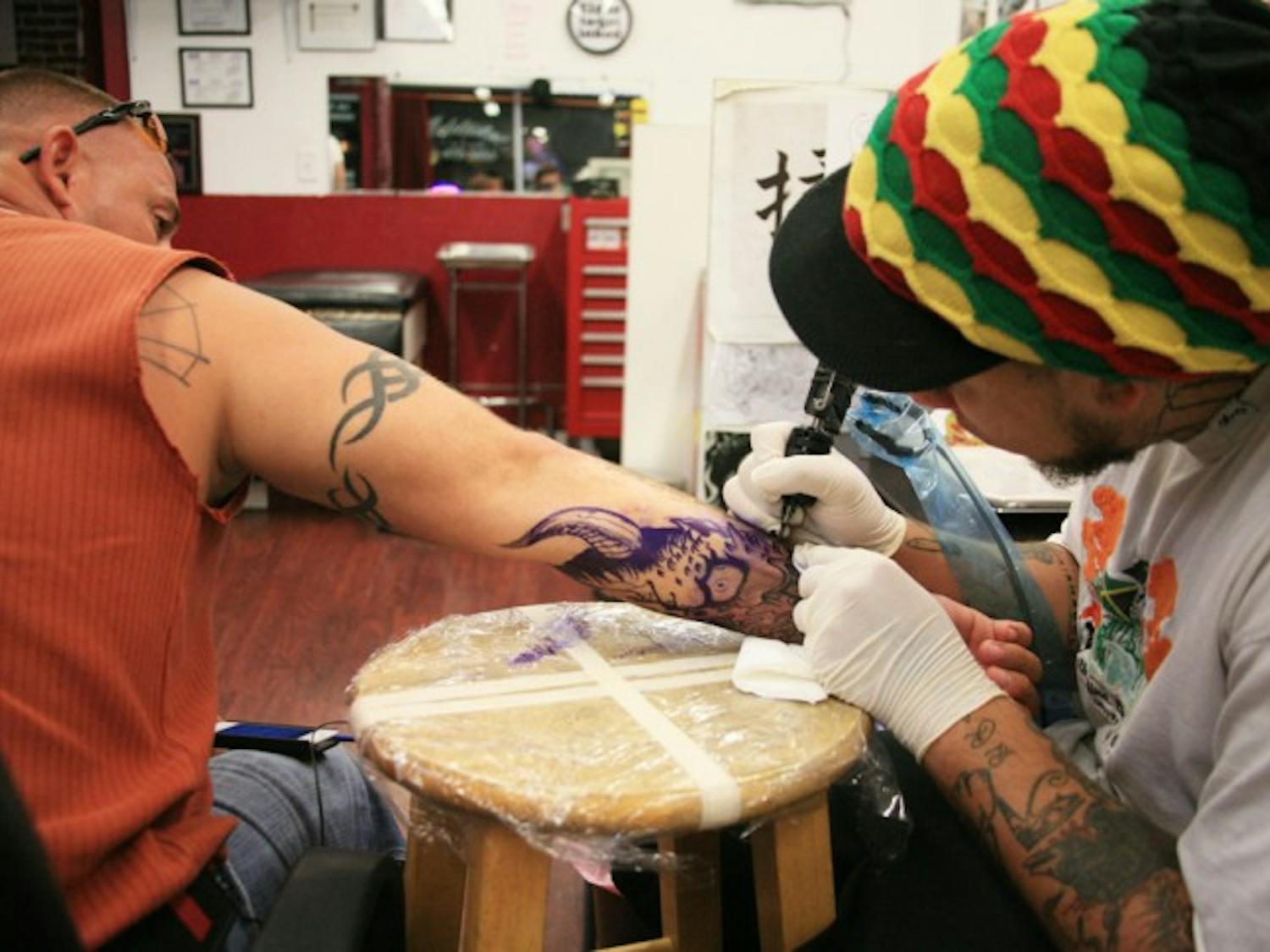 Santa Fe College health science freshman Charles Quinlan, 32, endures the pain of a custom tattoo by Mike Taylor, 23, at Addiction Tattoo and Piercing, 819 W. University Ave., on Sunday evening.