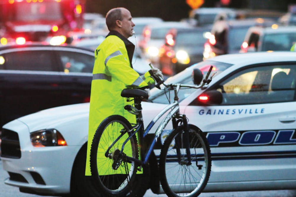 <p>Police service technician Robert Fox carries the victim’s bike from the scene of the collision Thursday evening. The victim was transported to the hospital following the incident, but the driver was not injured.</p>