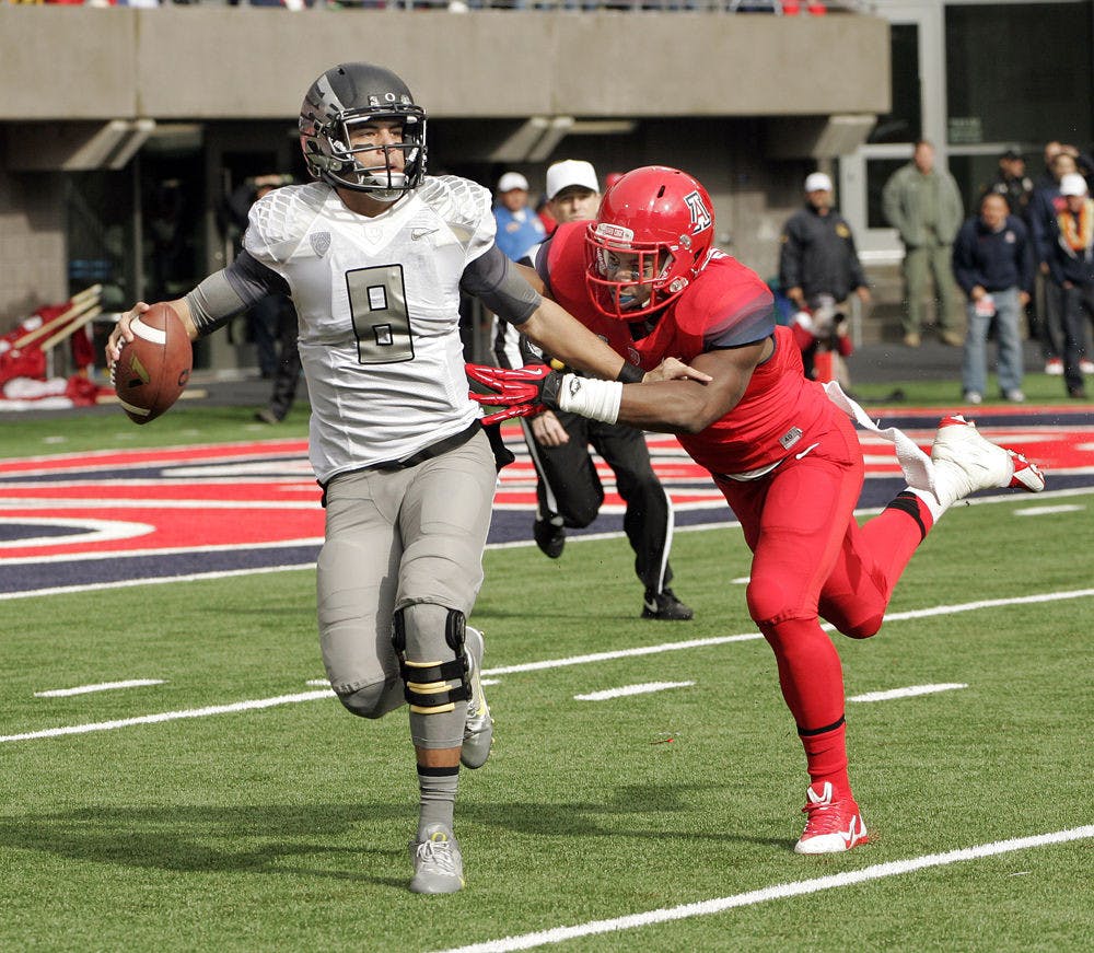 In this Nov. 23, 2013, file photo, Oregon's starting quarterback Marcus Mariota (8) is tackled in the backfield by Arizona's Marquis Flowers (2) in the first half of an NCAA college football game in Tucson, Ariz.