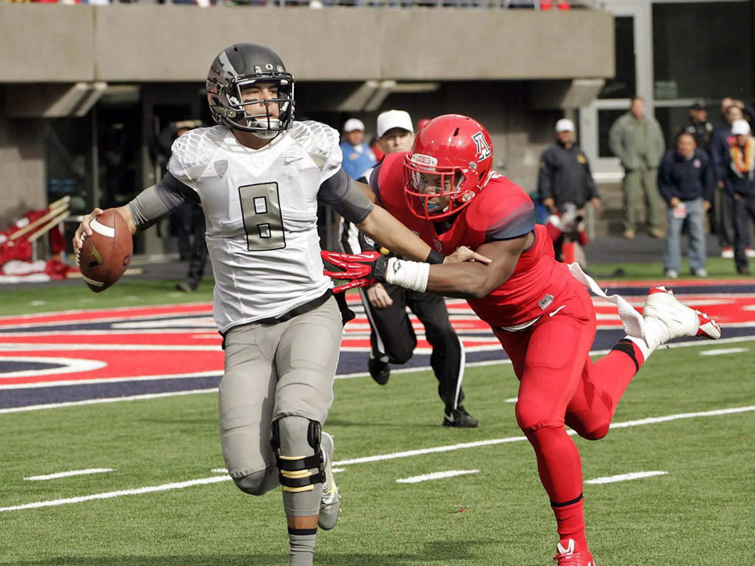 In this Nov. 23, 2013, file photo, Oregon's starting quarterback Marcus Mariota (8) is tackled in the backfield by Arizona's Marquis Flowers (2) in the first half of an NCAA college football game in Tucson, Ariz.
