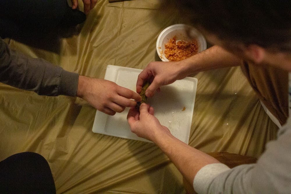 Ibrahim Ragab shows Adam Solomon how to properly roll  Mahshi, a of stuffed grape leaves dish, last Thursday night.