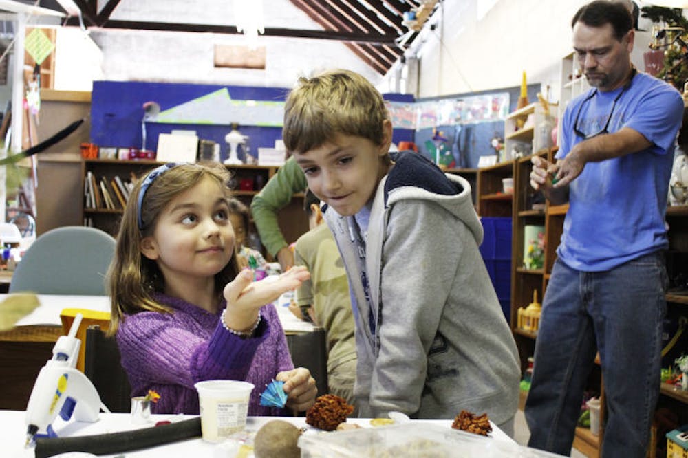 <p>Second-graders Claire Rotchford and Bryce Beckett create shadow boxes with garbage they collected from Littlewood Elementary School and other items at the Repurpose Project on Saturday.</p>