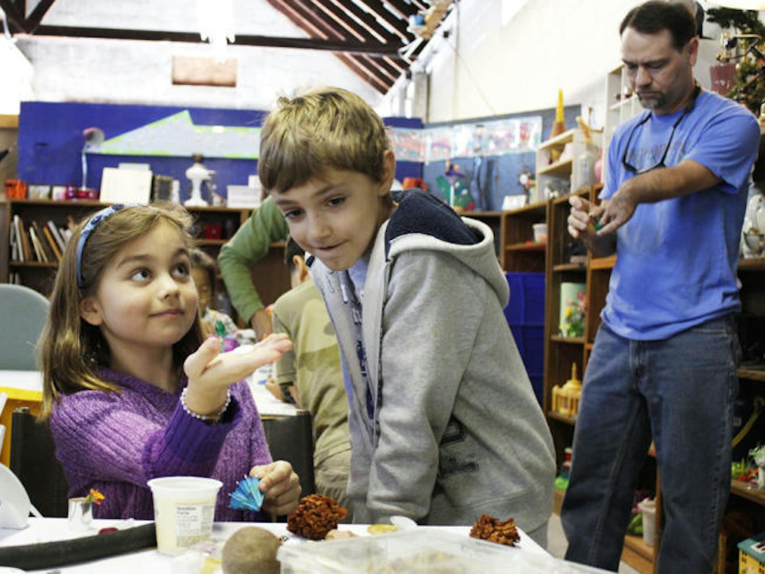 Second-graders Claire Rotchford and Bryce Beckett create shadow boxes with garbage they collected from Littlewood Elementary School and other items at the Repurpose Project on Saturday.