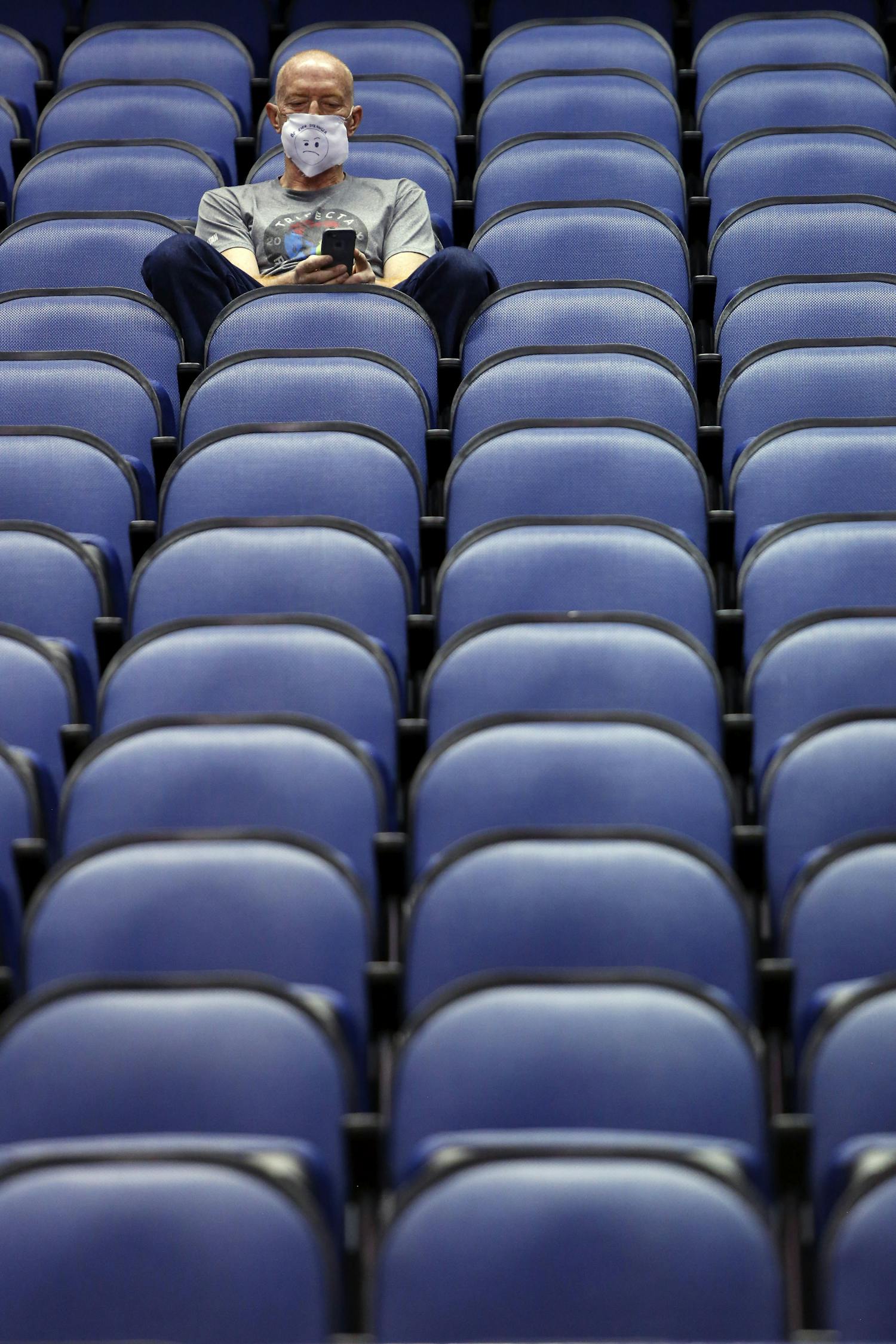 Mike Lemcke, from Richmond, Va., sits in an empty Greensboro Coliseum after the NCAA college basketball games were cancelled at the Atlantic Coast Conference tournament in Greensboro, N.C., Thursday, March 12, 2020. The biggest conferences in college sports all canceled their basketball tournaments because of the new coronavirus, seemingly putting the NCAA Tournament in doubt. (AP Photo/Ben McKeown)