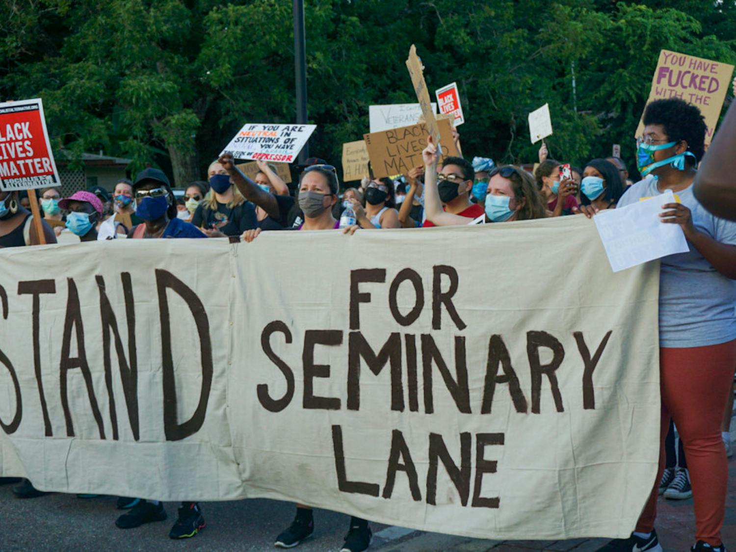 Protesters hold a banner that reads, "#StandForSeminaryLane," demanding that developers refrain from building luxury student apartments on land located in a historically Black community.
&nbsp;