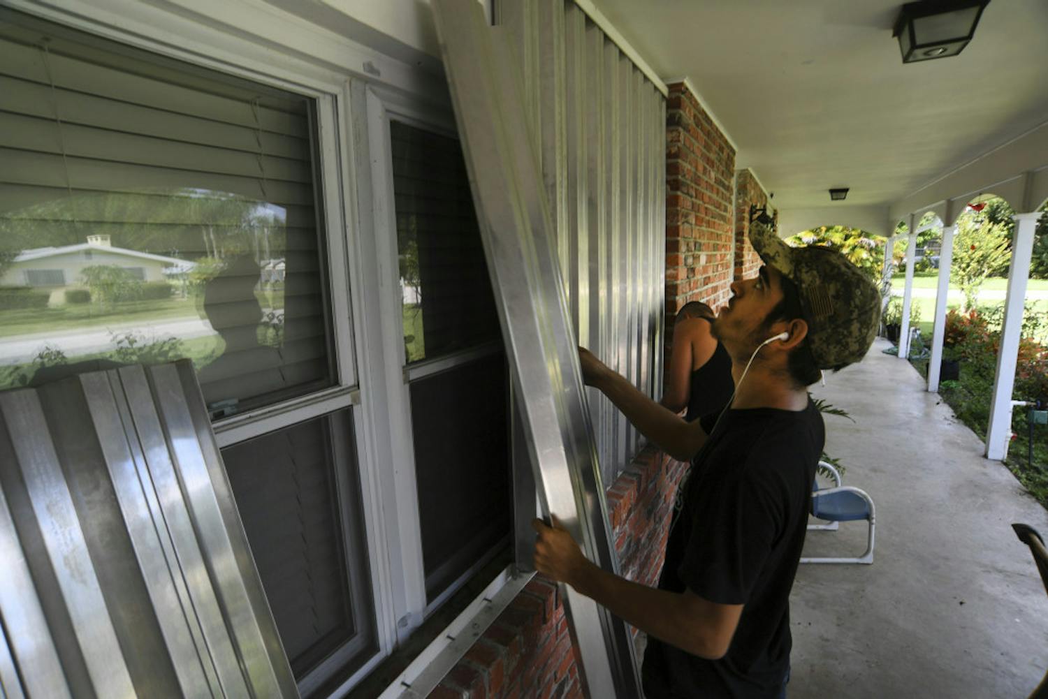 Richard Henson (foreground) and his uncle, Peter Henson, prepare their grandmother's house Thursday, Aug. 29, 2019, where she lives on Greenwood Drive in Fort Pierce, Fla., for the arrival of Hurricane Dorian. (Eric Hasert/TCPalm.com via AP)