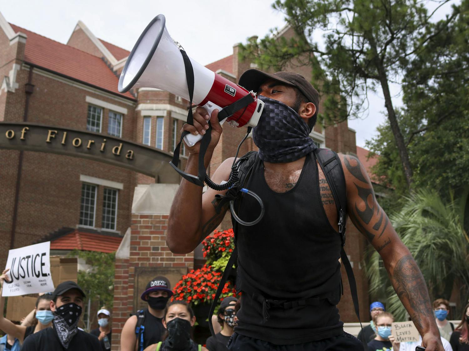 Daniel Brackett, a 24-year-old UF Physical Therapy Assistant and one of the organizers of the protest, shouts into a megaphone in front of a crowd of about 100 people at the intersection of 13th Street and University Avenue Wednesday as part of a protest against police brutality.