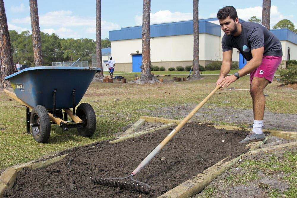 Jack Cheney, a UF marketing freshman, levels out dirt by the playground at Marjorie Kinnan Rawlings Elementary School on Sunday. The 18-year-old volunteered as part of a landscaping team during Project Makeover.